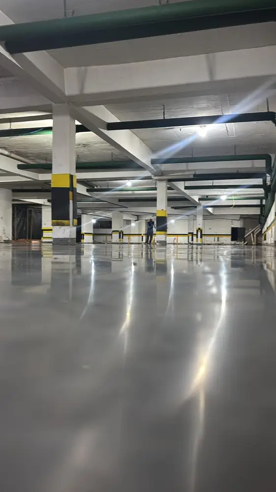 Reflexo das luminárias no concreto polido durante execução noturna