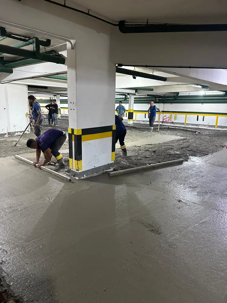 Equipe sarrafeando concreto fresco em estacionamento coberto
